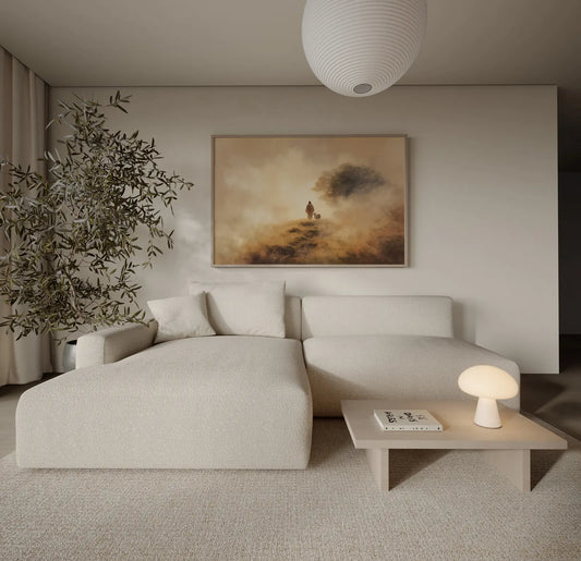 Framed painting of Jesus walking beside a lamb on a misty golden hillside path displayed in a neutral minimalist living room