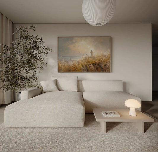 Framed painting of Jesus with arms outstretched in a golden wheat field by the sea displayed in a neutral minimalist living room