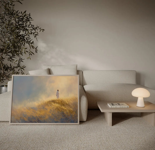 Framed painting of Jesus walking alone on a golden hillside toward the horizon displayed in a neutral minimalist living room