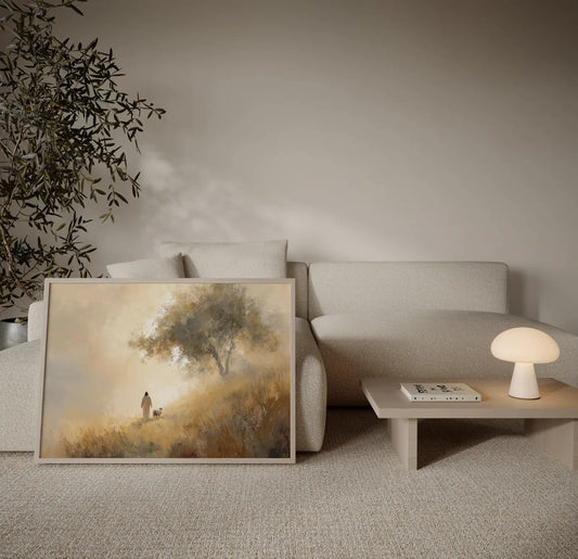 Framed painting of Jesus walking with a lamb toward a golden tree on a grassy hillside displayed in a neutral minimalist living room