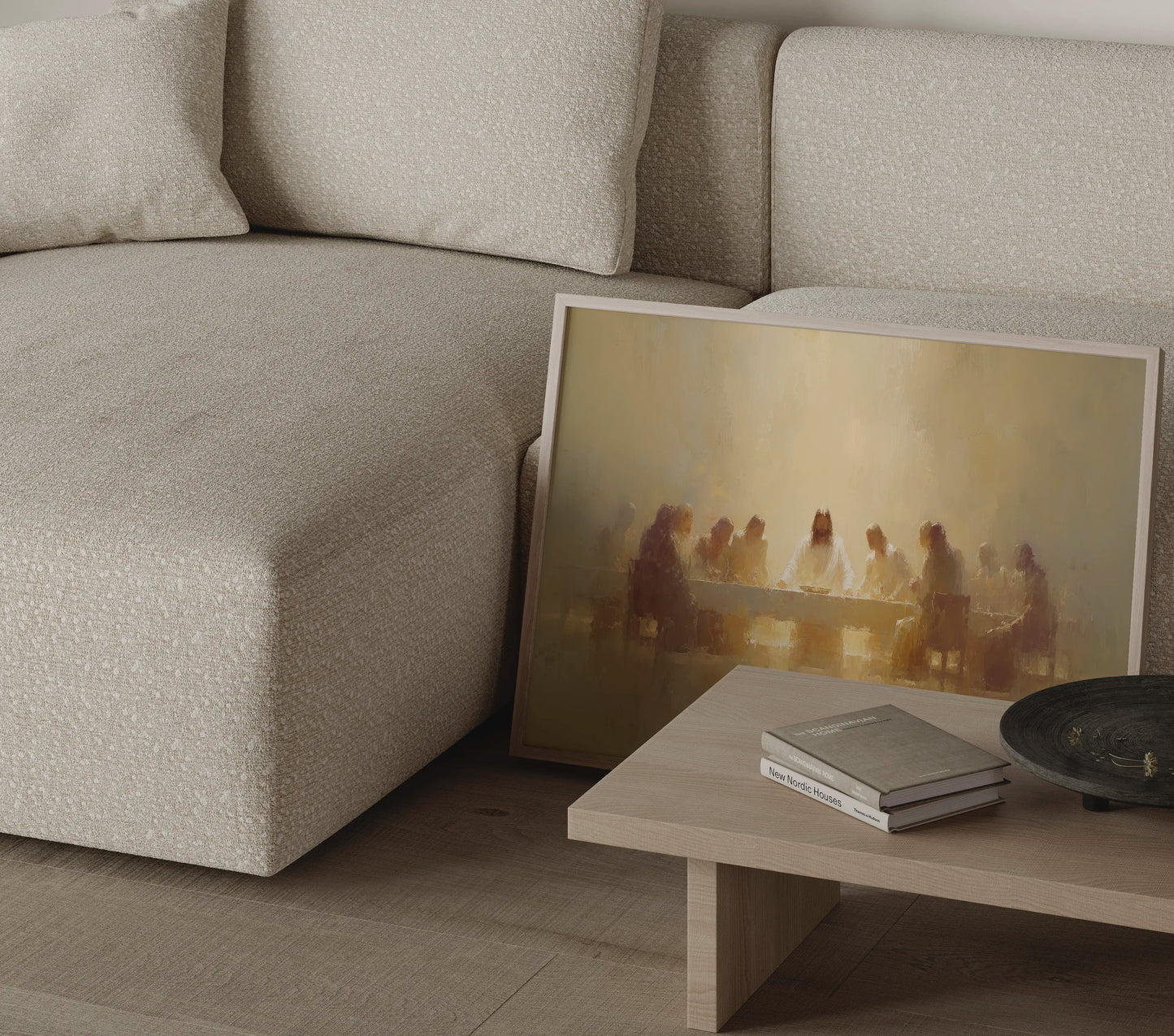 Golden-toned Last Supper painting in a thin frame beside a round side table in a neutral living room setting