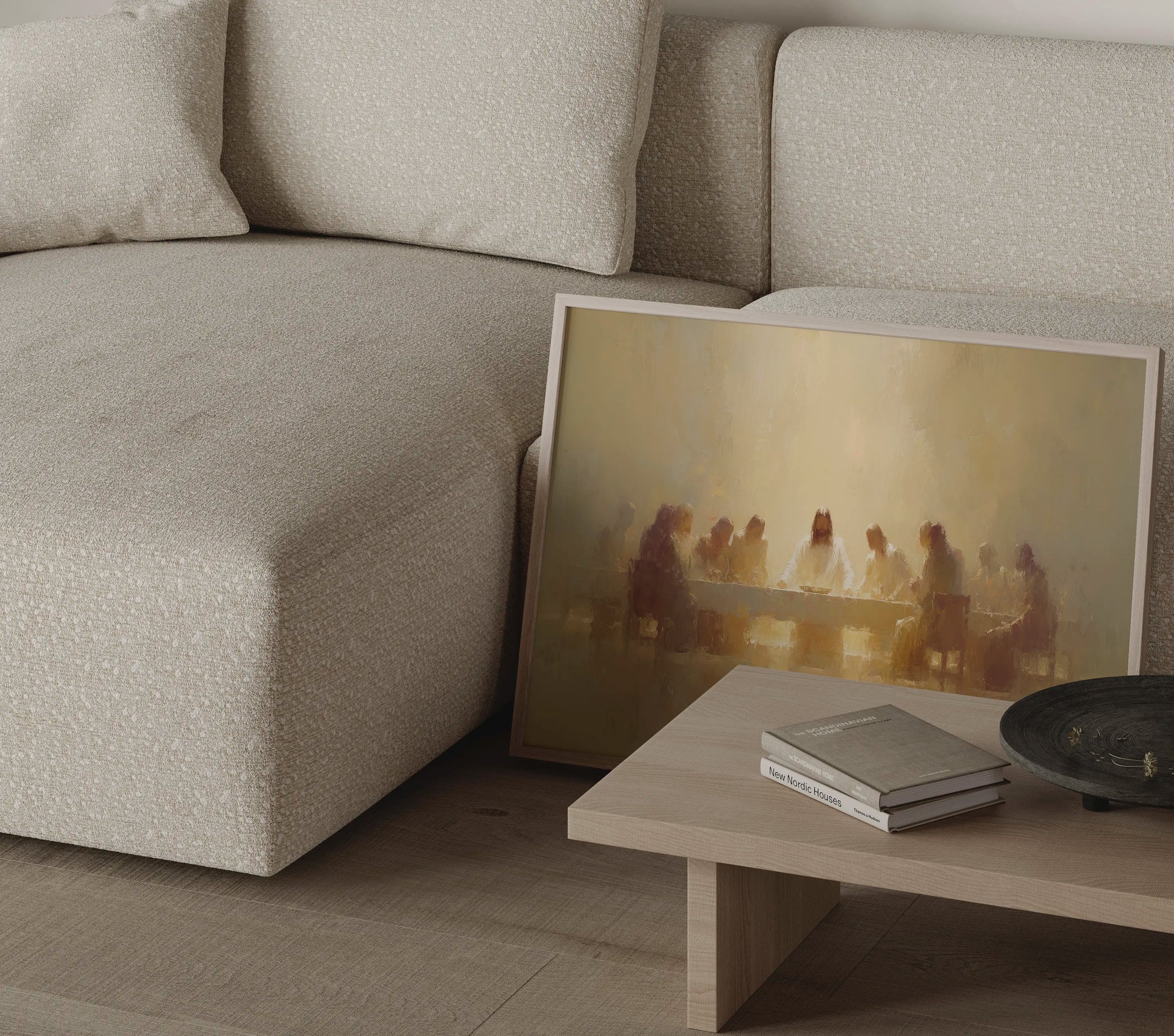 Golden-toned Last Supper painting in a thin frame beside a round side table in a neutral living room setting