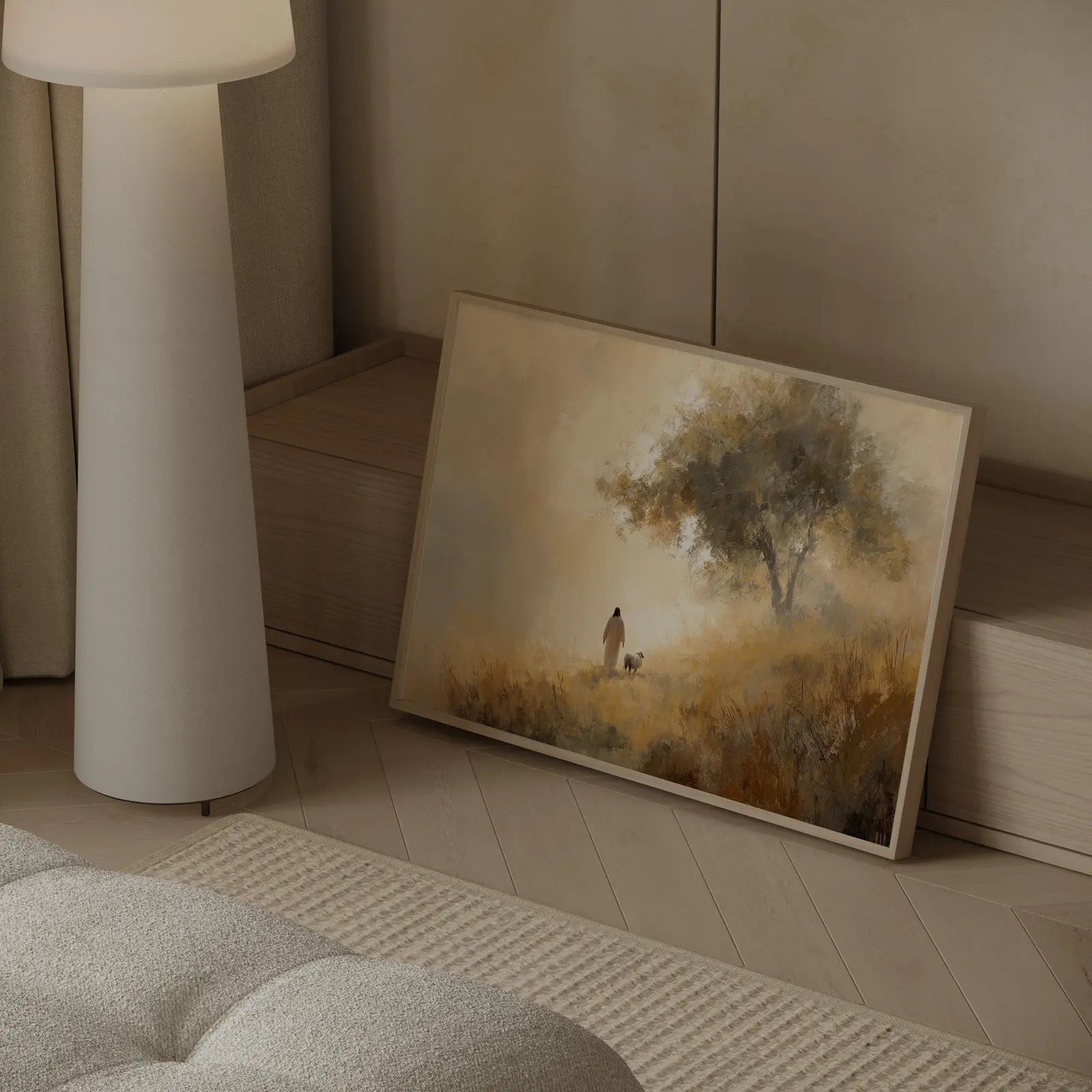 Good Shepherd painting of Jesus walking beside a lamb on a golden path toward an olive tree, framed and leaning beside a cream couch