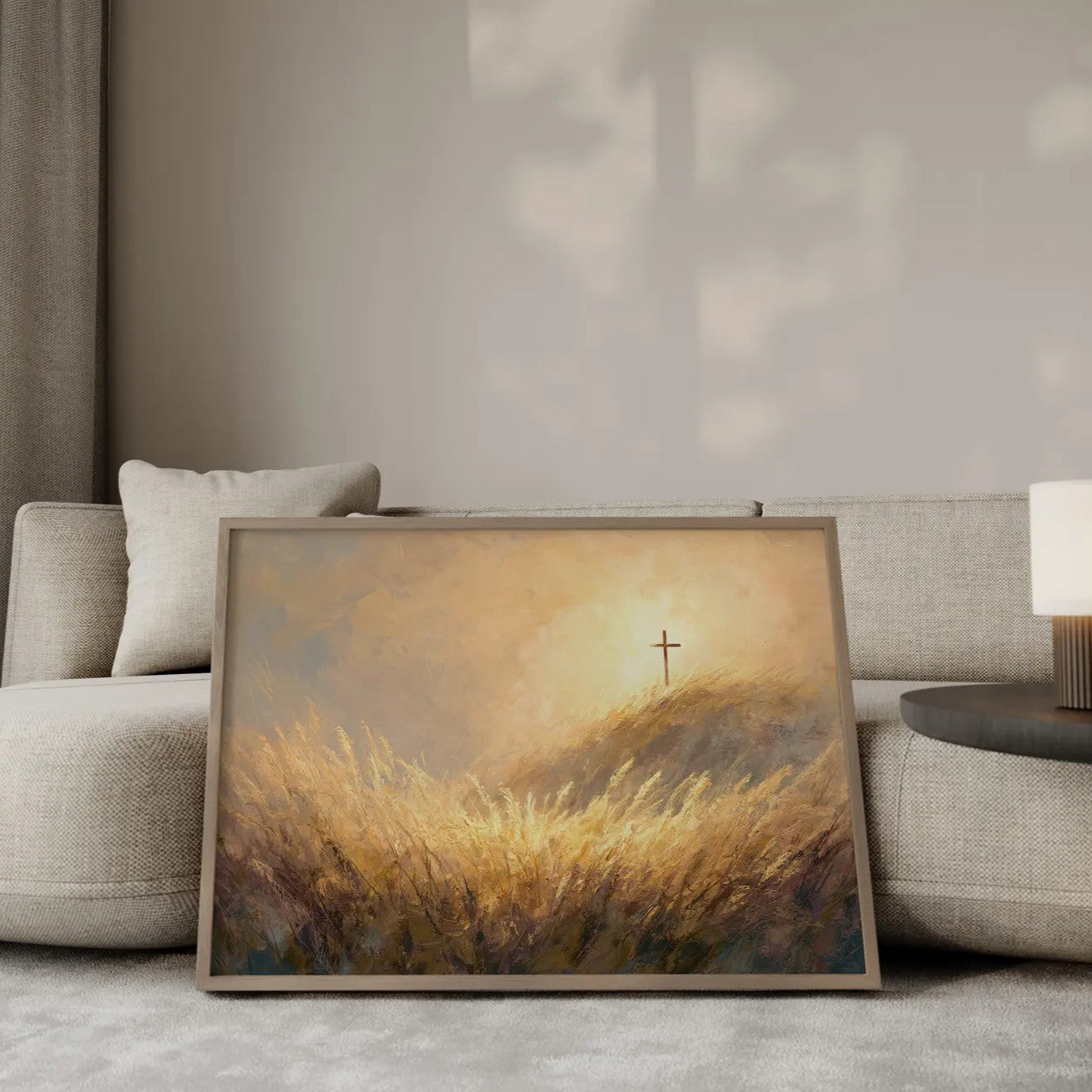 The Finished Work cross on golden hill wall art print in a gold frame leaning against a modern beige sofa – Christian home decor by JesusArtworks