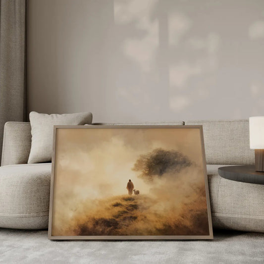 The Shepherd's Path Jesus walking with a lamb wall art print in a gold frame leaning against a modern beige sofa – Christian home decor by JesusArtworks